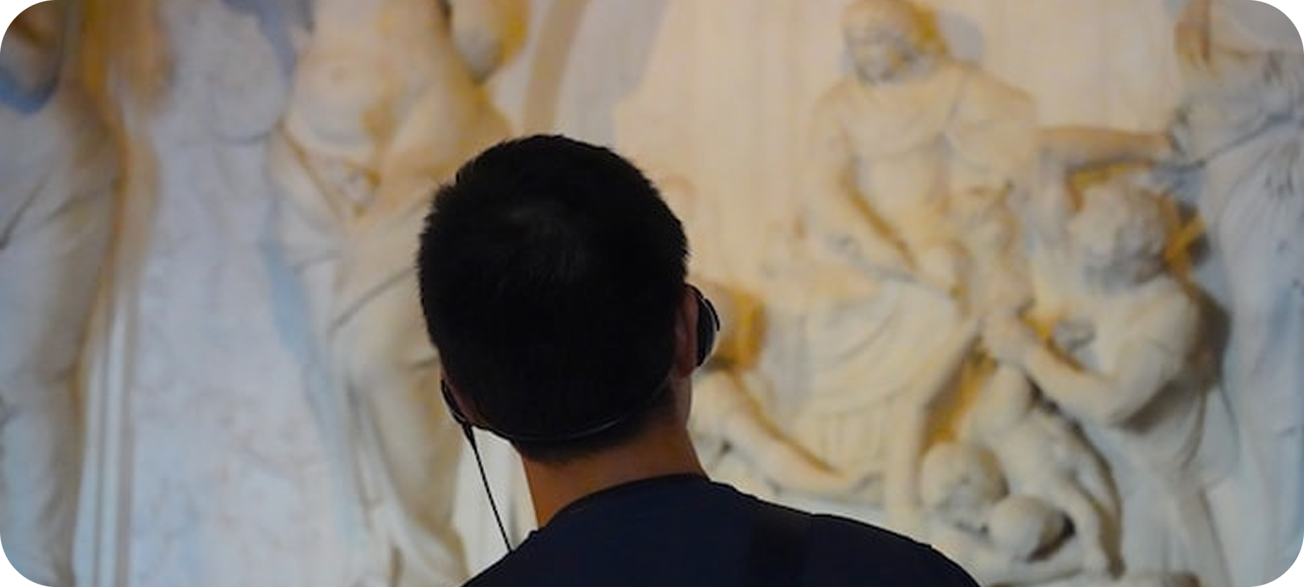 Person using an audio guide in a museum, illustrating how visitors can listen to multilingual explanations through QR Translator.